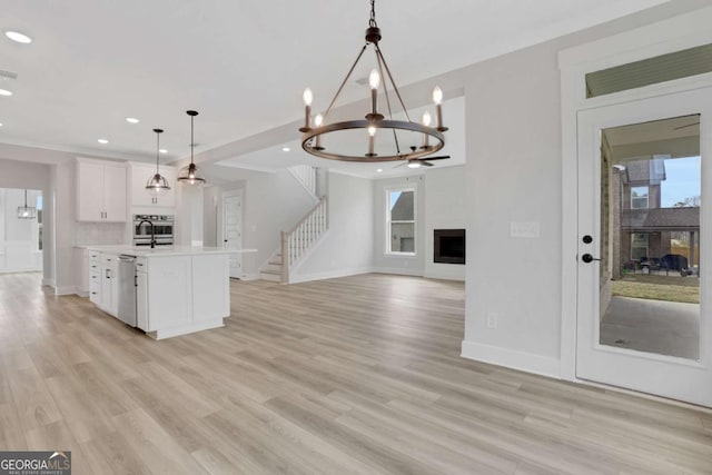 kitchen featuring open floor plan, baseboards, white cabinetry, a large fireplace, and light countertops