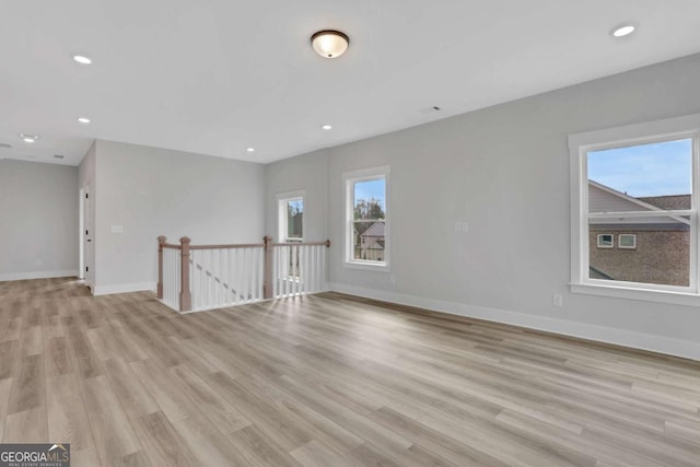 empty room featuring recessed lighting, baseboards, and light wood-type flooring