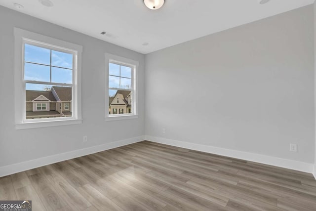 unfurnished room featuring visible vents, baseboards, and wood finished floors