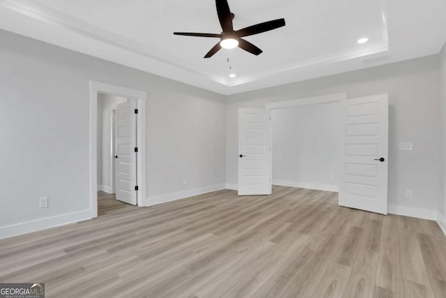unfurnished bedroom featuring ceiling fan, a tray ceiling, light wood-style flooring, baseboards, and recessed lighting