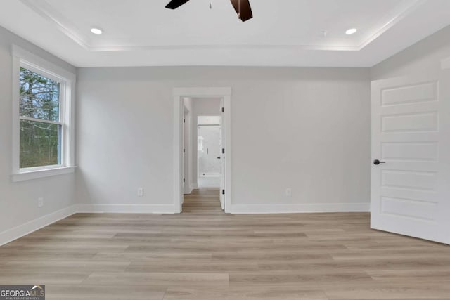 unfurnished bedroom with a raised ceiling, light wood-type flooring, crown molding, and baseboards