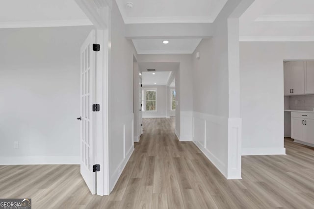 corridor featuring baseboards, crown molding, and light wood-style floors