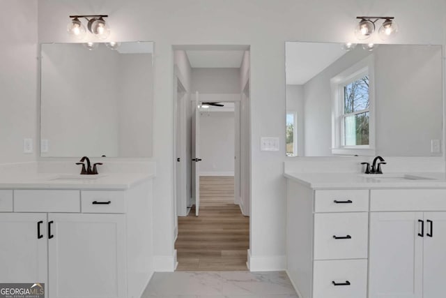bathroom with two vanities, marble finish floor, baseboards, and a sink