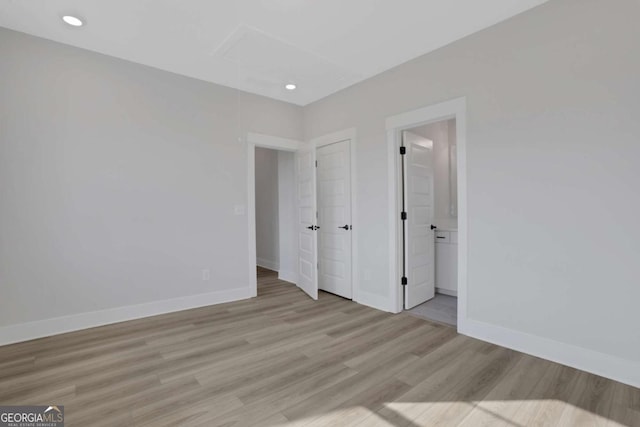 unfurnished bedroom featuring recessed lighting, light wood-type flooring, baseboards, and ensuite bathroom