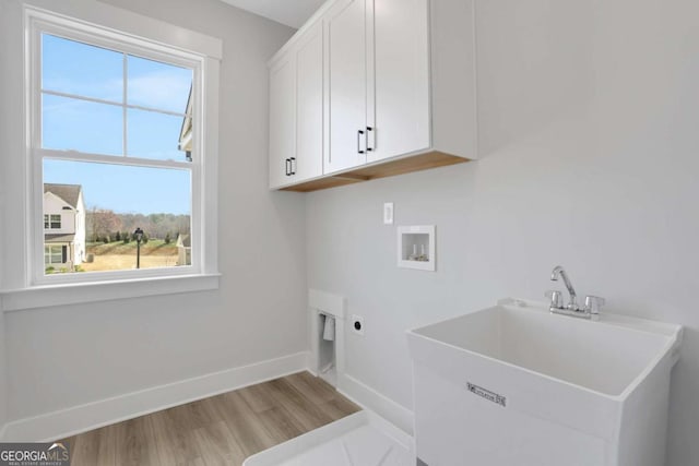 clothes washing area with hookup for an electric dryer, a sink, light wood-type flooring, hookup for a washing machine, and cabinet space