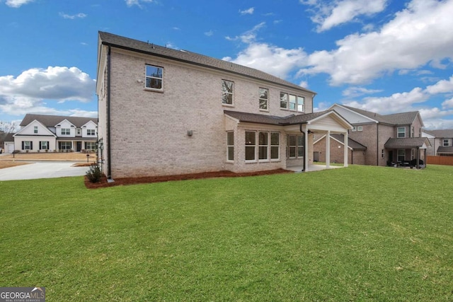 rear view of property with brick siding, a yard, and a patio