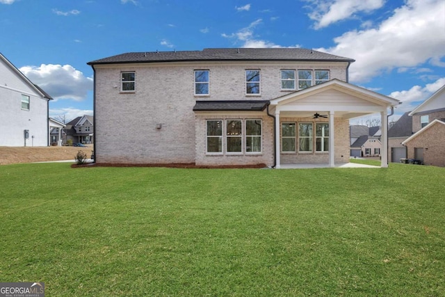 rear view of house featuring a yard, brick siding, and a ceiling fan