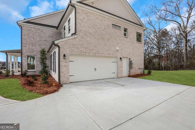view of property exterior with an attached garage, brick siding, and a yard