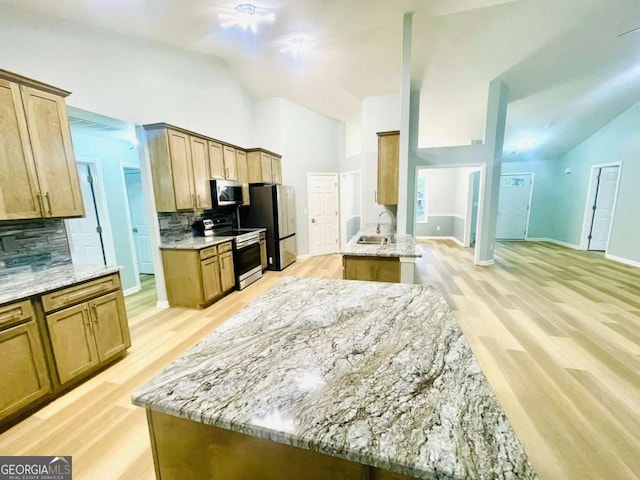 7675 Lanier View Rdg, Cumming, GA 30041 - kitchen featuring stainless steel appliances, backsplash, light stone counters, light wood-style flooring, and high vaulted ceiling