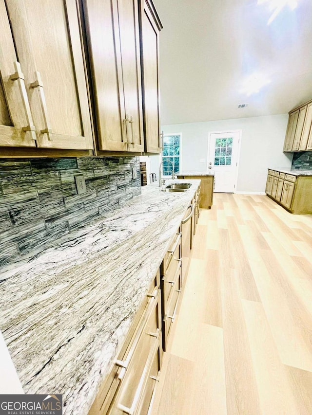 7675 Lanier View Rdg, Cumming, GA 30041 - kitchen featuring light wood-type flooring, decorative backsplash, a sink, light stone counters, and baseboards