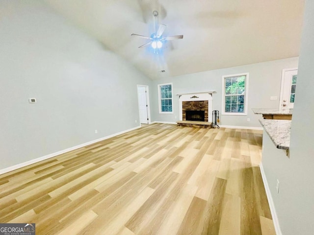 7675 Lanier View Rdg, Cumming, GA 30041 - unfurnished living room with a ceiling fan, light wood-style flooring, healthy amount of natural light, vaulted ceiling, and a stone fireplace