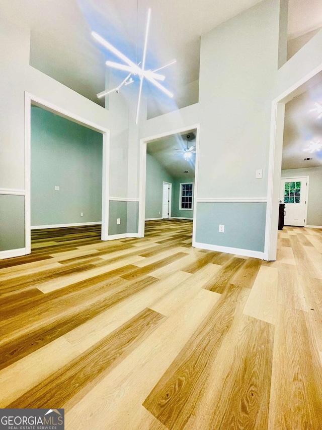 7675 Lanier View Rdg, Cumming, GA 30041 - unfurnished living room with wood finished floors, high vaulted ceiling, and ceiling fan