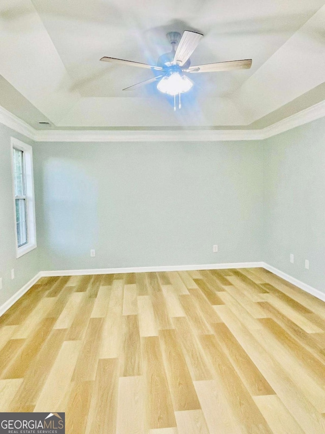 7675 Lanier View Rdg, Cumming, GA 30041 - empty room featuring a tray ceiling, light wood-type flooring, crown molding, ceiling fan, and baseboards