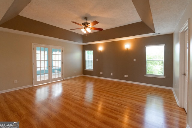 5 Gibson Rd, Newnan, GA 30263 - spare room featuring a textured ceiling, ceiling fan, a tray ceiling, light wood-type flooring, and baseboards