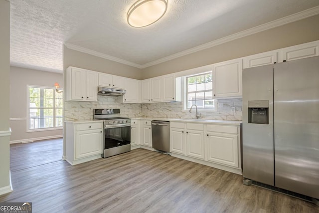 1331 Windage Ct SW, Marietta, GA 30008 - kitchen with stainless steel appliances, under cabinet range hood, light wood-style floors, white cabinetry, and ornamental molding