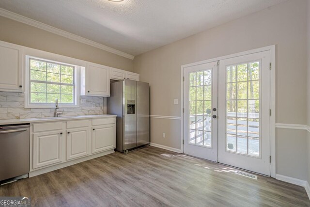 1331 Windage Ct SW, Marietta, GA 30008 - kitchen with appliances with stainless steel finishes, french doors, backsplash, light countertops, and light wood-style flooring