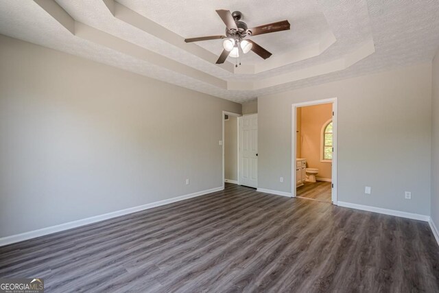 1331 Windage Ct SW, Marietta, GA 30008 - unfurnished bedroom featuring a raised ceiling, dark wood finished floors, a textured ceiling, ensuite bathroom, and ceiling fan