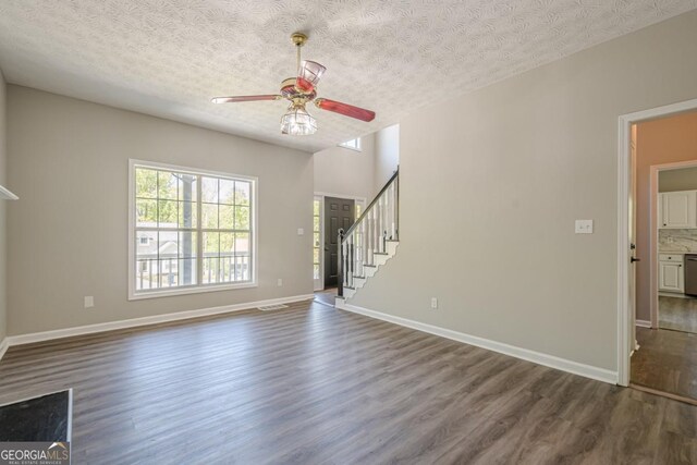 1331 Windage Ct SW, Marietta, GA 30008 - unfurnished living room featuring dark wood-style floors, a ceiling fan, a textured ceiling, and stairs
