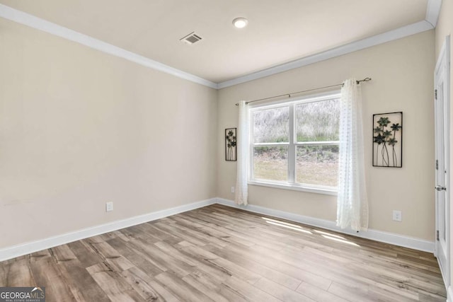 empty room featuring wood finished floors, visible vents, crown molding, and baseboards