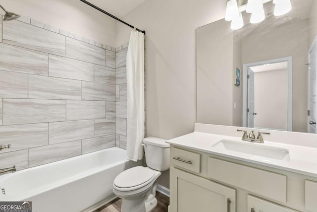 full bath featuring wood finished floors, vanity, baseboards, shower / tub combo, and toilet