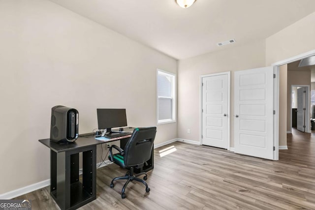 home office with wood finished floors, visible vents, and baseboards