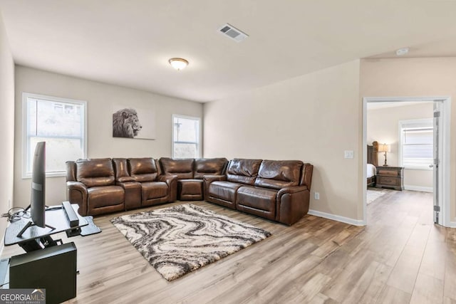 living room with wood finished floors, visible vents, and baseboards