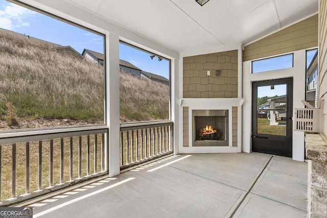 unfurnished sunroom featuring a warm lit fireplace and a healthy amount of sunlight