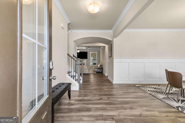 entrance foyer with wood finished floors, arched walkways, stairs, and crown molding