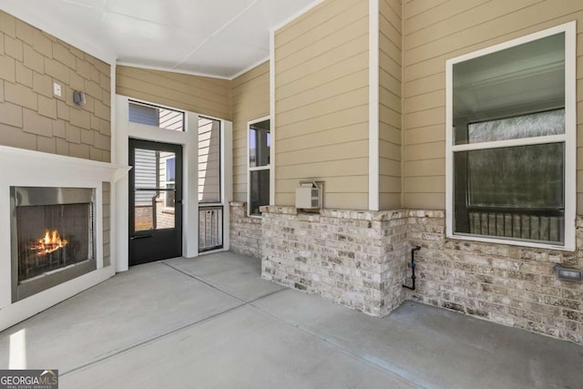 entrance to property featuring a patio area and a lit fireplace