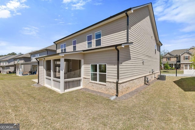 back of property featuring a residential view, central air condition unit, a sunroom, and a lawn
