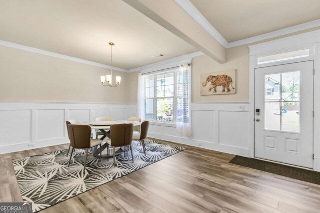 dining area featuring a decorative wall, a notable chandelier, and light wood-style floors