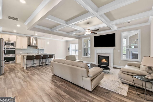 living area featuring a fireplace with flush hearth, a wealth of natural light, and visible vents