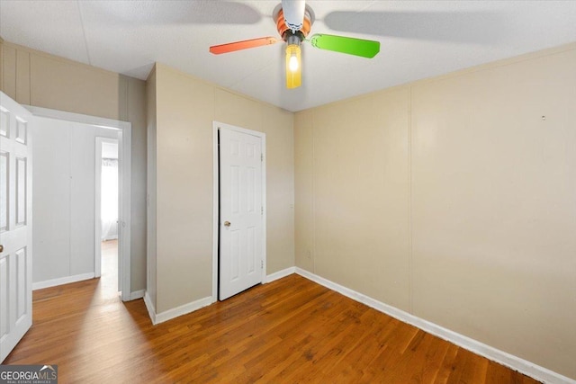 unfurnished bedroom featuring baseboards, wood finished floors, and ceiling fan