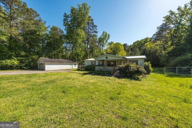 view of yard with a porch, an outdoor structure, fence, and a detached garage