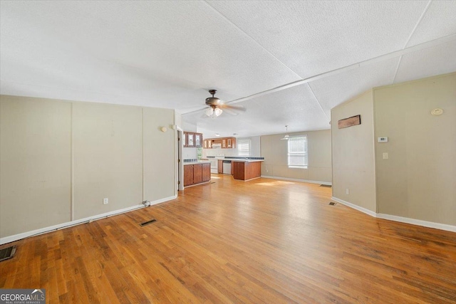 unfurnished living room with light wood finished floors, visible vents, baseboards, a textured ceiling, and ceiling fan