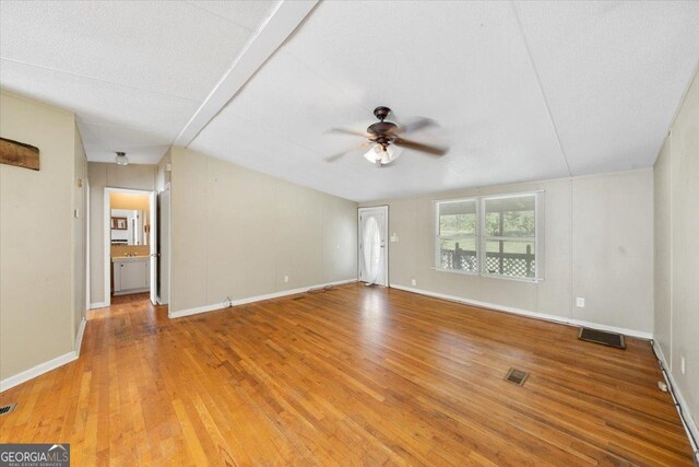 unfurnished living room with baseboards, a ceiling fan, visible vents, and light wood-type flooring