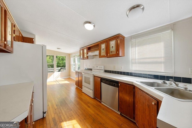 kitchen featuring a sink, light wood-style floors, white appliances, light countertops, and under cabinet range hood