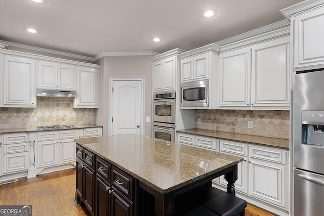 kitchen with decorative backsplash, recessed lighting, white cabinetry, under cabinet range hood, and appliances with stainless steel finishes