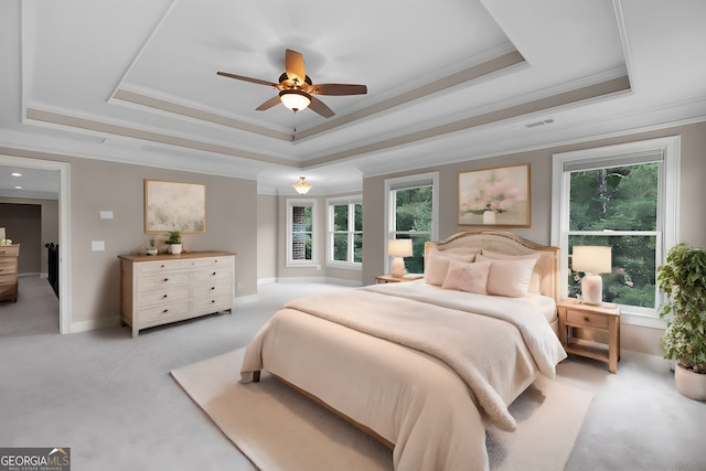 bedroom with ornamental molding, a tray ceiling, and multiple windows