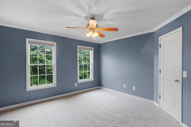 carpeted empty room with crown molding, a ceiling fan, and baseboards