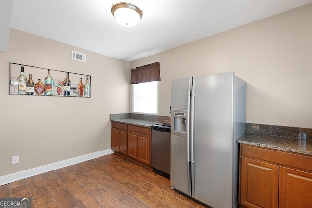 kitchen with stove, visible vents, stainless steel fridge, and brown cabinetry