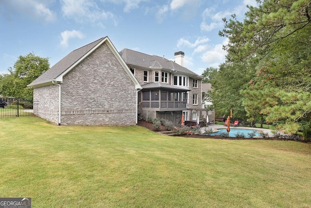 rear view of property with a lawn, fence, a chimney, and a sunroom