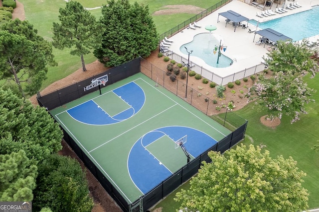 view of sport court featuring a community pool, fence, and a yard