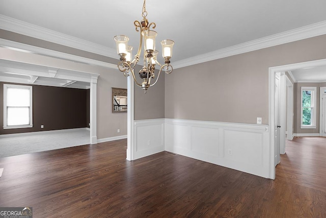 unfurnished dining area featuring baseboards, a chandelier, ornamental molding, and wood finished floors