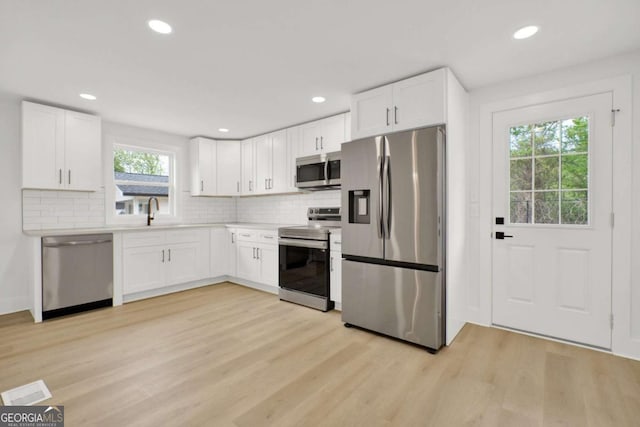 kitchen featuring white cabinets, stainless steel appliances, and light wood-style floors