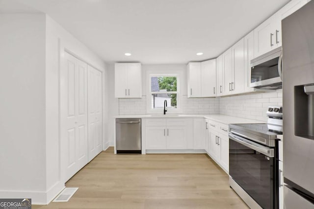 kitchen featuring a sink, white cabinetry, decorative backsplash, light countertops, and appliances with stainless steel finishes