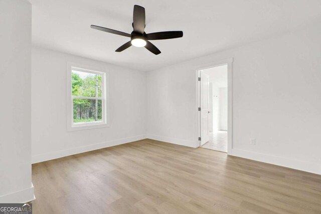 empty room with a ceiling fan, baseboards, and light wood-style floors