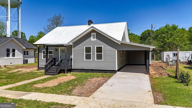 bungalow-style home featuring a carport, a front lawn, metal roof, and concrete driveway