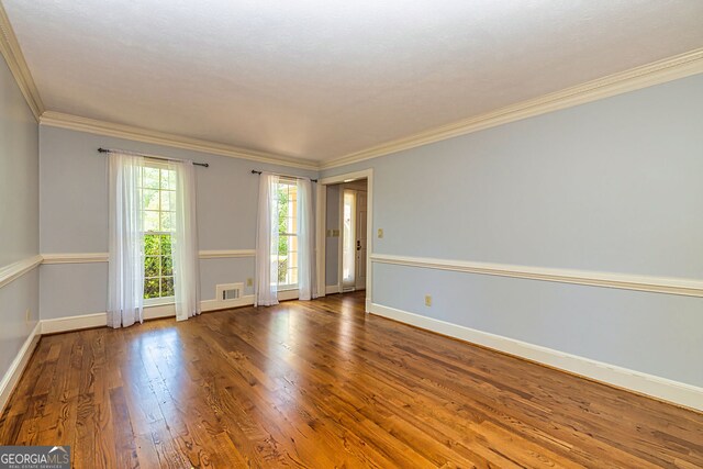 unfurnished room with baseboards, wood finished floors, and ornamental molding