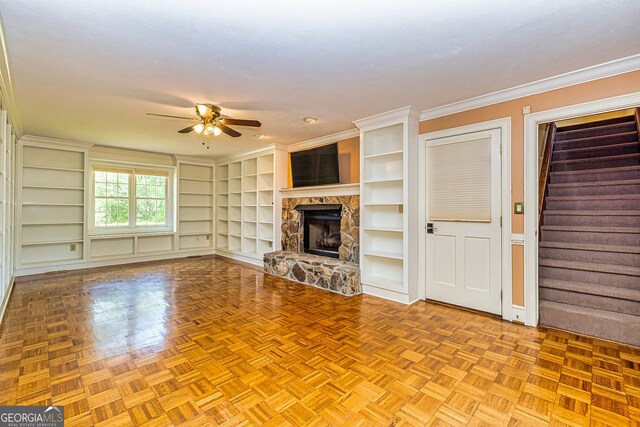 unfurnished living room with a ceiling fan, a fireplace, crown molding, stairway, and built in features